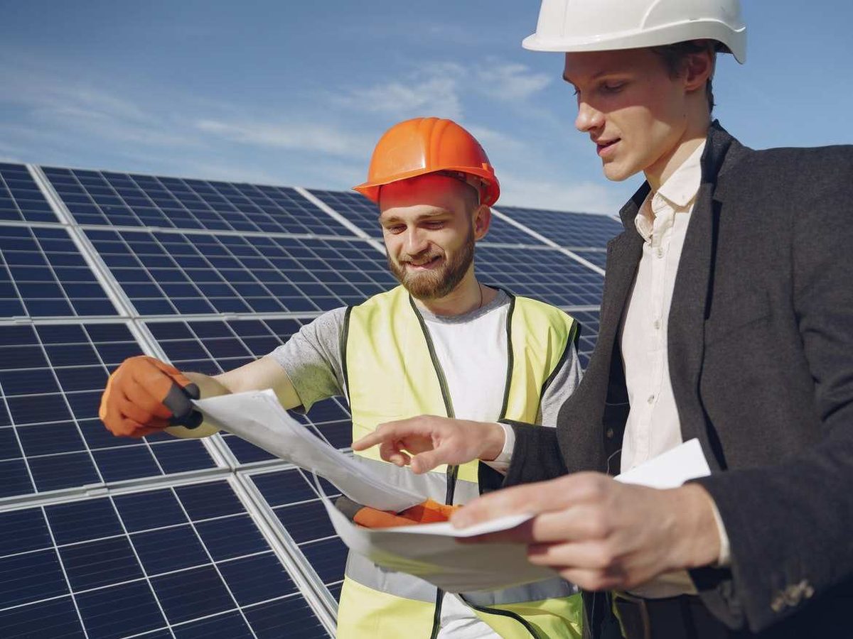 Energetikai szakértő és mérnök helyszíni felmérési dokumentumot egyeztet egy napelemsor mellett